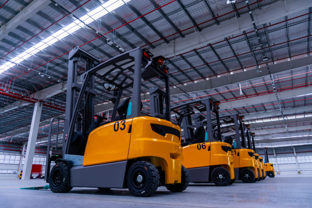 Line of yellow counterbalance forklifts in a warehouse.