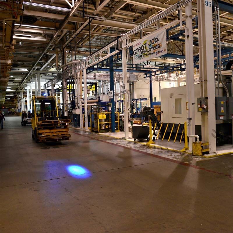 Forklift in a warehouse environment with a blue spot light projected. 